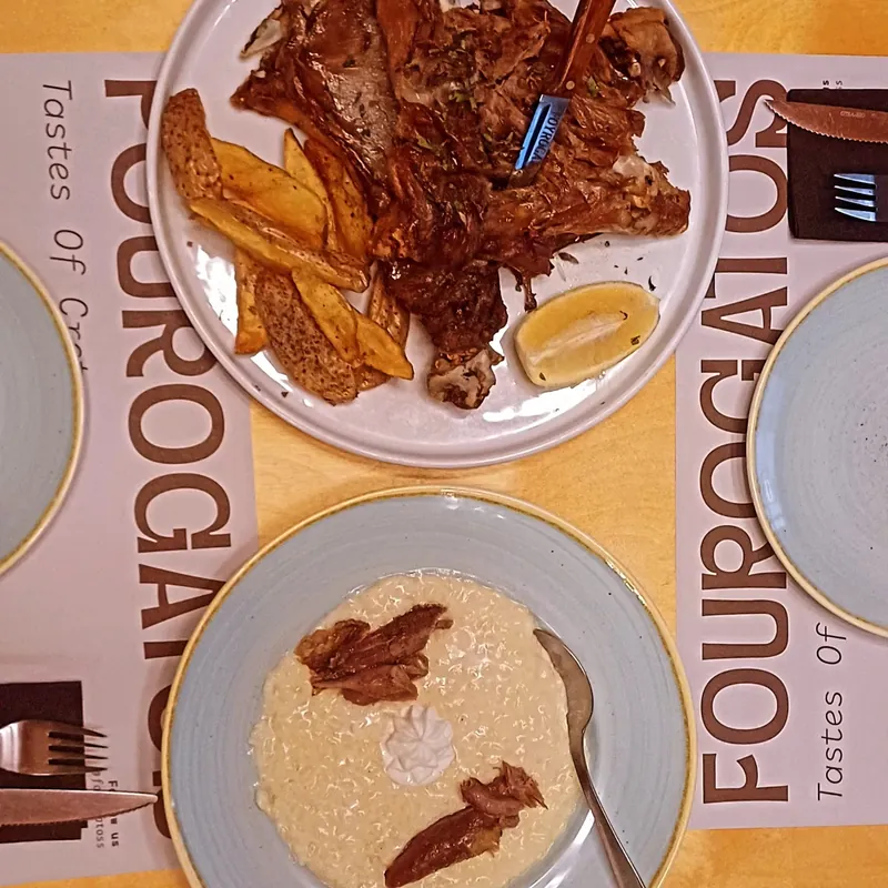 Από πάνω: ψητό κρέας με πατάτες και λεμόνι και ένα πιάτο ρύζι, πάνω στα σουπλά με το «Fourogatos, Tastes of Crete».